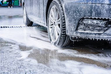 Sabunlu köpükle kaplı bir araç bir oto yıkama tesisinde temizleniyor. Su ve köpük bir araya gelince, araba yüzeyi parlıyor, iyice yıkanmasını sağlıyor.