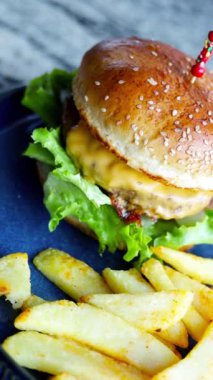 Mavi tabakta kızarmış patatesli bir Amerikan hamburgeri. Sağlıksız gıda konsepti. Kafede ya da restoranda çizburger ve patates kızartması, fast food. 
