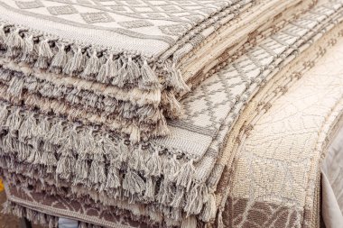 Güzelce işlenmiş örülmüş tekstil sergisi canlı bir pazarda duruyor. Kumaşlar karmaşık desenler ve yumuşak renkler içeriyor. Alışverişçiler için yerel ürünleri keşfetmek için davetkar bir ortam yaratıyor..