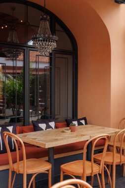 Ahşap bir masa ve şık sandalyelerle rahat oturmak Avrupa tarzı bir açık hava kafe veya restoran havası yaratıyor.