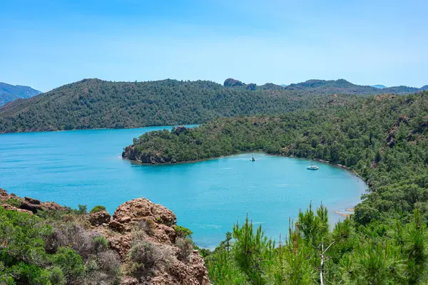Tepeler ve ağaçlarla çevrili canlı turkuaz sular, rahatlama ve keşif için mükemmel..