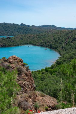 Tepeler ve ağaçlarla çevrili canlı turkuaz sular, rahatlama ve keşif için mükemmel..