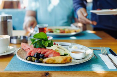 Bir grup arkadaş bir restoranda sakin bir yemek yer, çeşitli yiyecek ve içeceklerin tadını çıkarırlar. Garson geleneksel Türk usulü yemekler servis ediyor. Yaz tatili kafesi, her şey dahil.