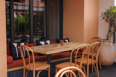 Ahşap bir masa ve şık sandalyelerle rahat oturmak Avrupa tarzı bir açık hava kafe veya restoran havası yaratıyor.