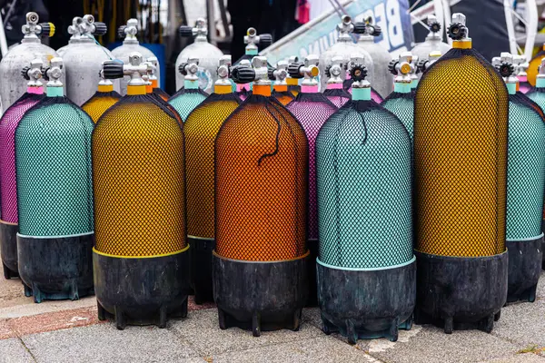 Güneşli bir günde bir dalış mağazasının önünde canlı renklerde çeşitli tüplü dalış tankları sergileniyor. Yaz tatilleri, turizm, geziler ve aktif hobiler konsepti