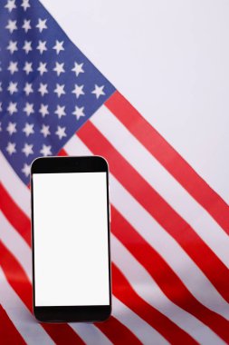 Model tasarım metni veya ABD ulusal bayrağının arkaplanındaki ürün için modern akıllı telefon üzerindeki boş beyaz ekran