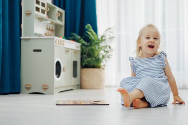 Çocuk çocuk yerde rengarenk bir bulmacanın keyfini çıkarırken yumuşak ışık ve yeşilliklerle çevrili.