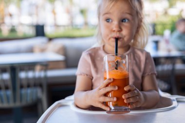 Çocuk ellerinde bir bardak taze havuç suyu.
