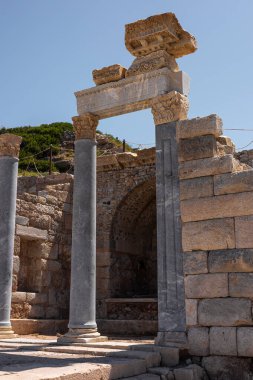 Türkiye 'deki antik harabelerde sütunlu taş bir kemer var. Yapı, açık mavi gökyüzüne karşı tarihsel mimarinin kalıntılarını gösteriyor..