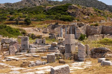 Türkiye 'de taş sütunları ve patikaları olan antik kalıntılar. Yeşillik, dağlık bir zemin üzerine kurulmuş arkeolojik alanı çevrelemektedir..