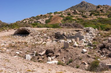 Türkiye 'de taş yapılar ve kemer yolu bulunan antik kalıntılar. Manzara kayalık tepeleri ve açık mavi gökyüzünün altındaki seyrek bitki örtüsünü içerir..