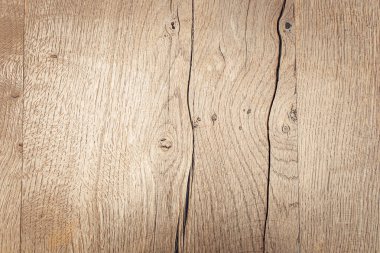 Dokulu ahşap bir yüzeye yakın çekim ve doğal tahıl desenleri. Ahşap, görünür düğümler ve çizgilerle açık renklidir ve kırsal bir görünüm yaratır..