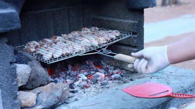 Bacadan yükselen alevlerle dolu taştan bir şömine. Ortam ağaçlarla çevrili. Toplanma için doğal bir atmosfer yaratıyor..