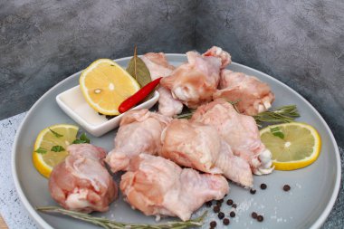 Tabağında baharat olan çiğ tavuk kanatları.