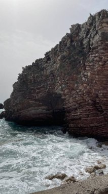 Çakıl taşlı kumsaldaki güzel kayalar. Rafailovici tatil köyleri. Karadağ. Adriyatik Denizi. Yaz güneşli bir gün. Deniz kenarı tatil konsepti. Yüksek kalite fotoğraf