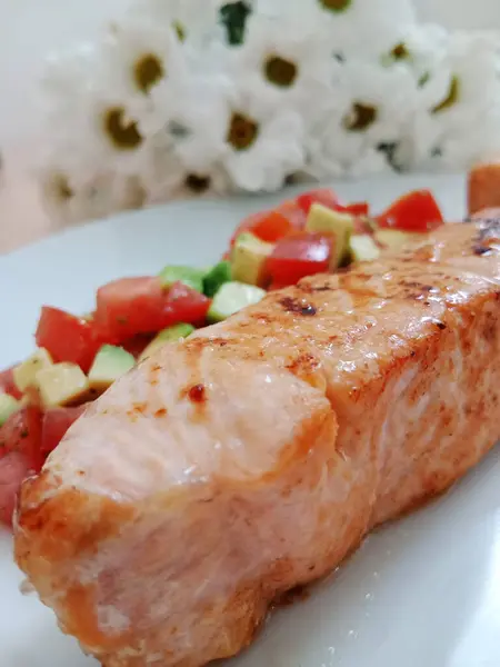 Healthy breakfast, lunch, light dinner. Grilled salmon with tomato and avacado salad on a white plate.