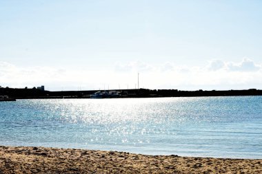 Beyaz kumlu ve mavi gökyüzü olan bir sahilin dikey görüntüsü.