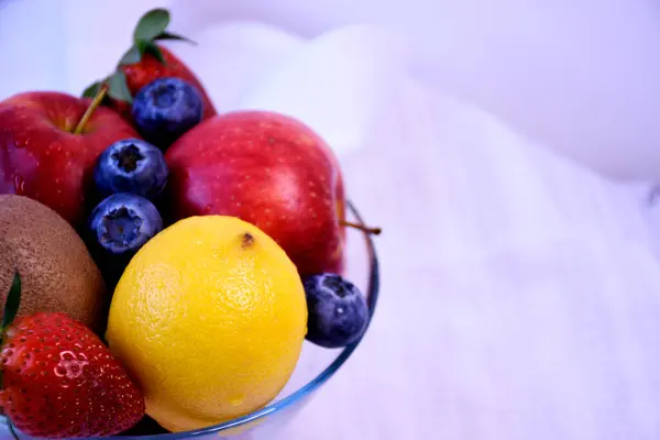 Beyaz arka planda cam vazoda meyve ve böğürtlen.