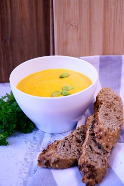 Kremalı ve fıstıklı balkabağı kremalı çorba ve taze ekmek.