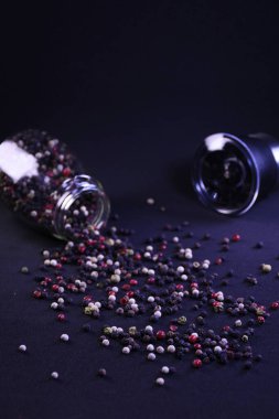 Biber taneleri, siyah bir arka planda, yüzeydeki bir biberlikten yayılmış.