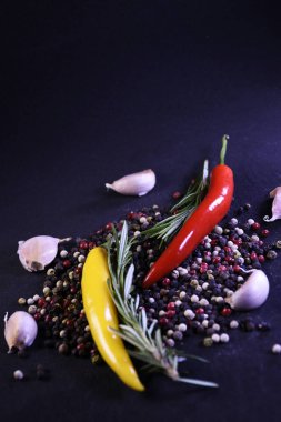 Yemeklerin tadını geliştirmek için baharatlar. Biber, sarımsak, siyah arka planda biberiye..