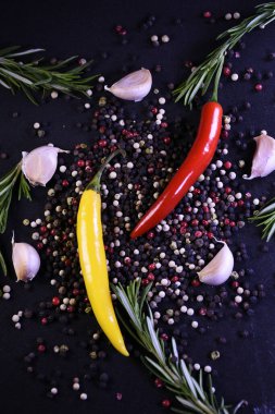Yemeklerin tadını geliştirmek için baharatlar. Biber, sarımsak, siyah arka planda biberiye..