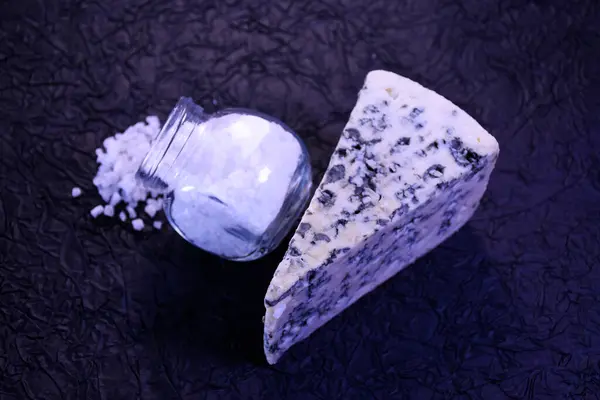 Siyah arka planda mavi peynir ve kaba tuz.