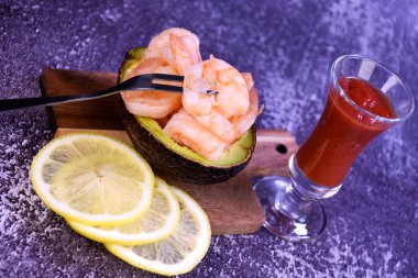 Limon dilimleri ve kokteylle birlikte yarım bir avokadoda karides.