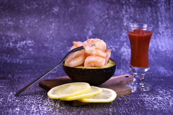 Limon dilimleri ve kokteylle birlikte yarım bir avokadoda karides.