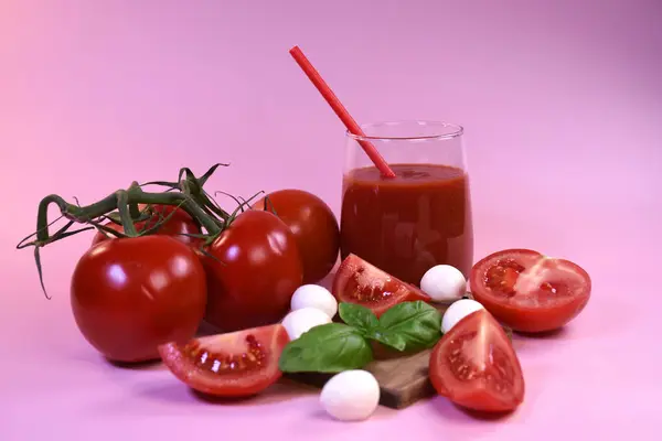 Taze domatesli domates suyu, mozzarella ve pembe arka planda fesleğen.