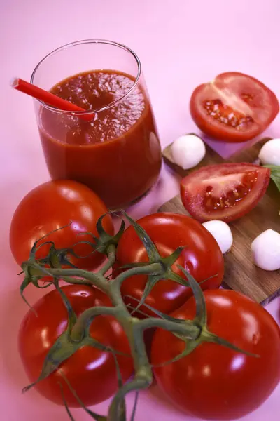 Taze domatesli domates suyu, mozzarella ve pembe arka planda fesleğen.