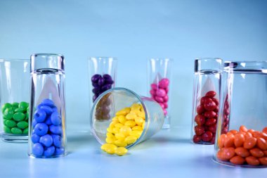 Mavi arka planda şeffaf gözlüklerle çok renkli parlak şekerler.