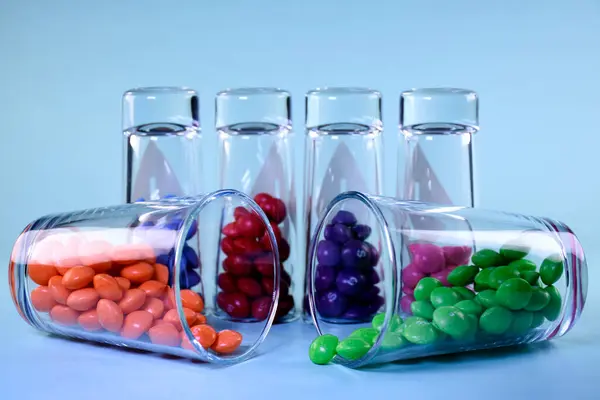 Mavi arka planda şeffaf gözlüklerle çok renkli parlak şekerler.