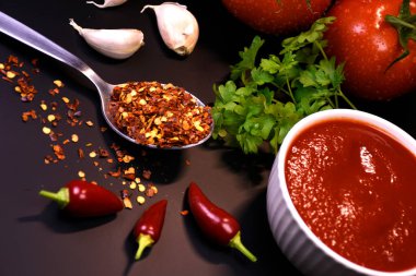 Ketçap yapımında kullanılan malzemeler. Masanın üzerinde domates ve maydanozlu ketçap var..