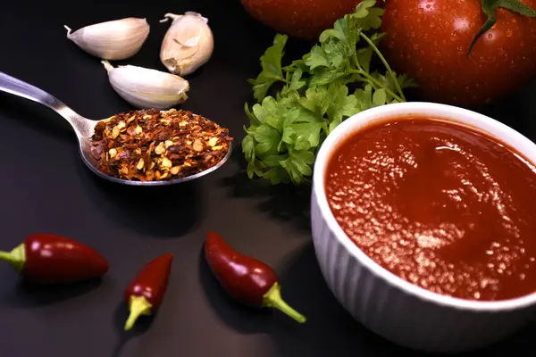 Ketçap yapımında kullanılan malzemeler. Masanın üzerinde domates ve maydanozlu ketçap var..