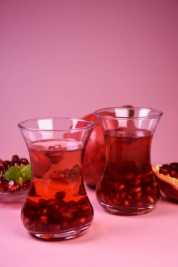 İki bardak nar suyu ve taze meyveler. Bir bardakta Türk nar çayı ve taze nar. Yüzeyde taze nane ve nar tohumları.