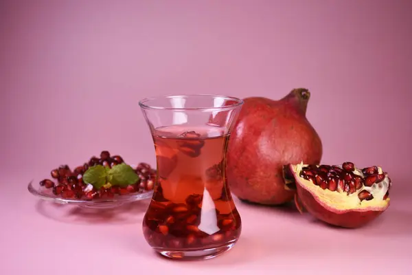 İki bardak nar suyu ve taze meyveler. Bir bardakta Türk nar çayı ve taze nar. Yüzeyde taze nane ve nar tohumları.