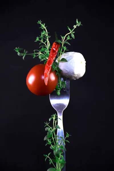 Taze kiraz domatesleri ve fesleğen yaprakları. Sebze dolu bir hayat. Salata için malzemeler. Alışılmadık bir sunum. Çatala batırılmış domates ve mozarella..