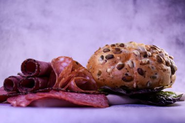 Jambonlu taze ekmek. Sosis hazır. Sosisler, sosisler, panodaki farklı sosisler. Tohumlu çörek. Gri arkaplan.