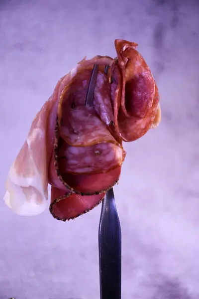 Domuz pastırmasına sarılmış sosis. Sosis hazır. Sosisler, sosisler, çatala saplanmış farklı sosisler. Gri arkaplan.