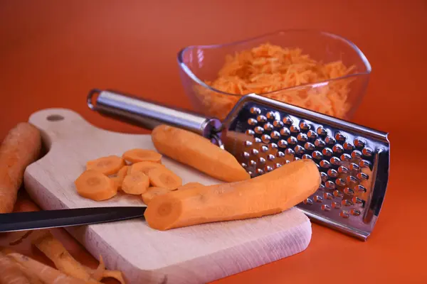 Pişirmeye hazır taze havuçlar. Tahta bir kesme tahtasına dilimlenmiş havuç ve havuç ile birlikte bir kase içinde dilimlenmiş havuç konur..