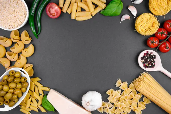 Çerçevenin çevresindeki koyu gri arka planda yer alan İtalyan mutfağının ortasında boş bir alan bırakarak. İçindekiler: çeşitli makarna türleri (erişte yuvaları, farfalle, penne, büyük kabuklar)), 