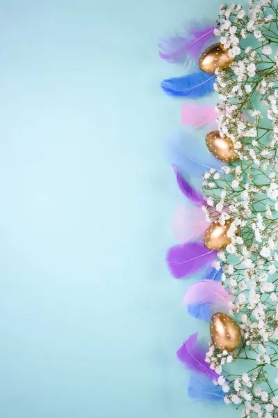 Beyaz puantiyeli altın Paskalya yumurtaları ve pastel turkuaz arka planda beyaz çingene çiçekleri..