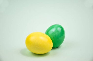İki Paskalya yumurtası, sarı ve yeşil, açık arkaplanda.