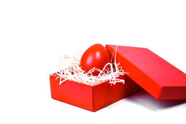 Red Easter egg in a gift box with decorative straw on a white background. clipart