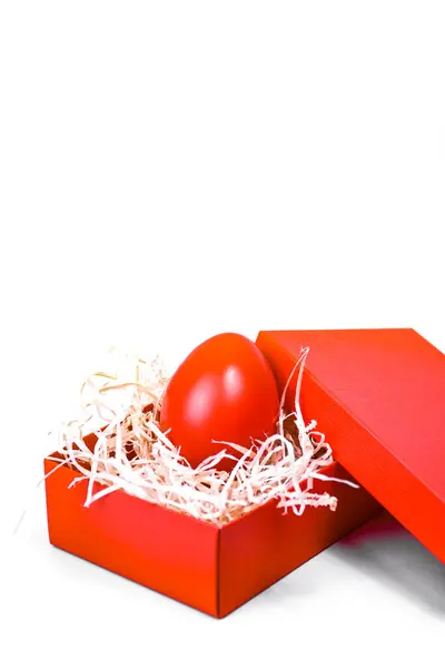 Kırmızı Paskalya yumurtası hediye kutusunda beyaz arka planda dekoratif pipetle.