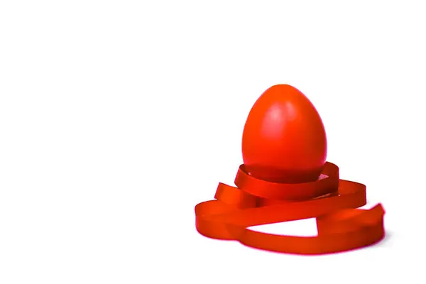 Kırmızı Paskalya yumurtası, beyaz arka planda kırmızı kurdeleli..