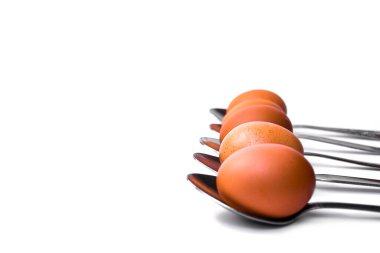 Kahverengi yumurtalar beyaz arka planda kaşıklar halinde dizilmiş.