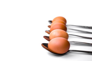 Kahverengi yumurtalar beyaz arka planda kaşıklar halinde dizilmiş.