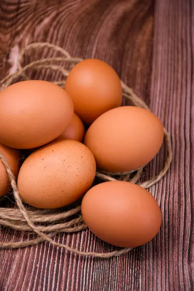 Kahverengi tavuk yumurtaları sert sicimle çevrili ahşap bir yüzeyde yatar..